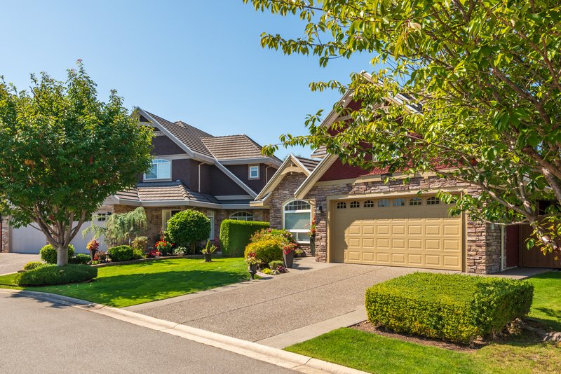 El frente de una casa con jardín y arboles verdes en un día fresco