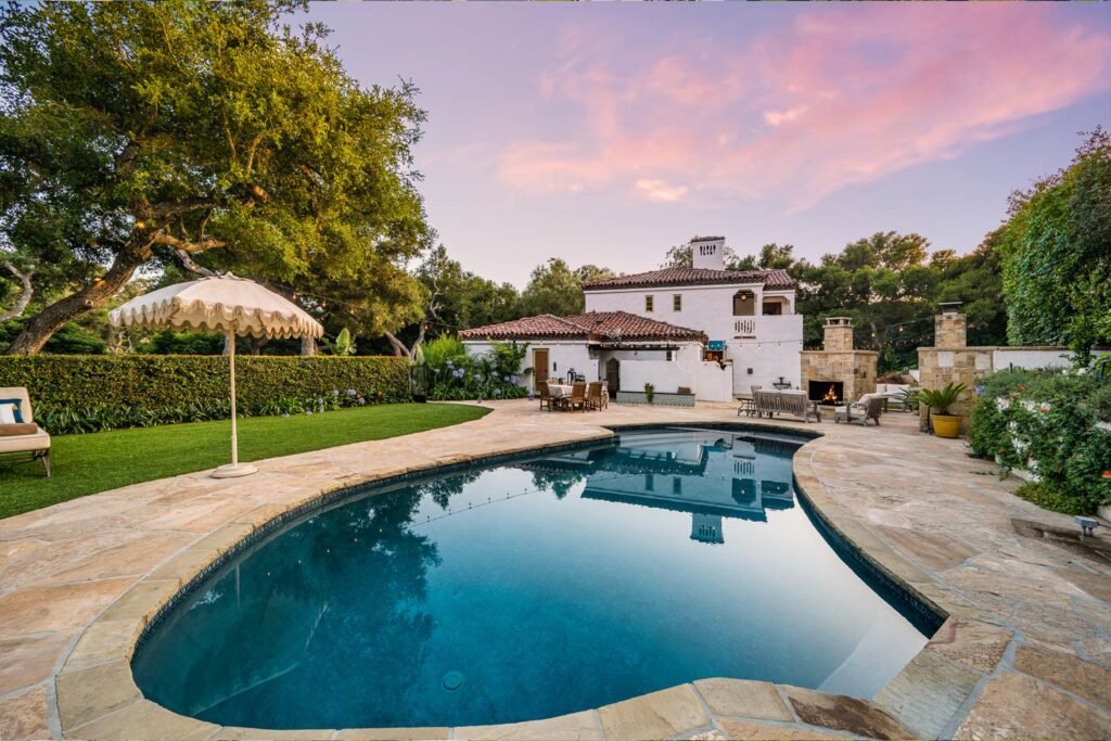Una gran alberca con casa alrededor con jardín y un bonito atardecer